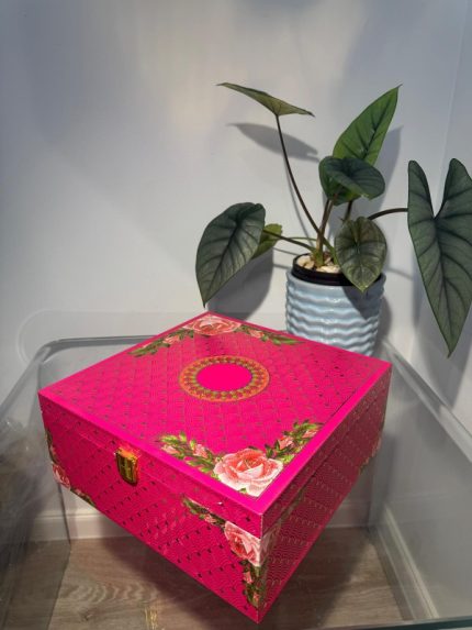 Vibrant pink floral 4-jar gift box with gold pattern and rose design on corners placed on glass table